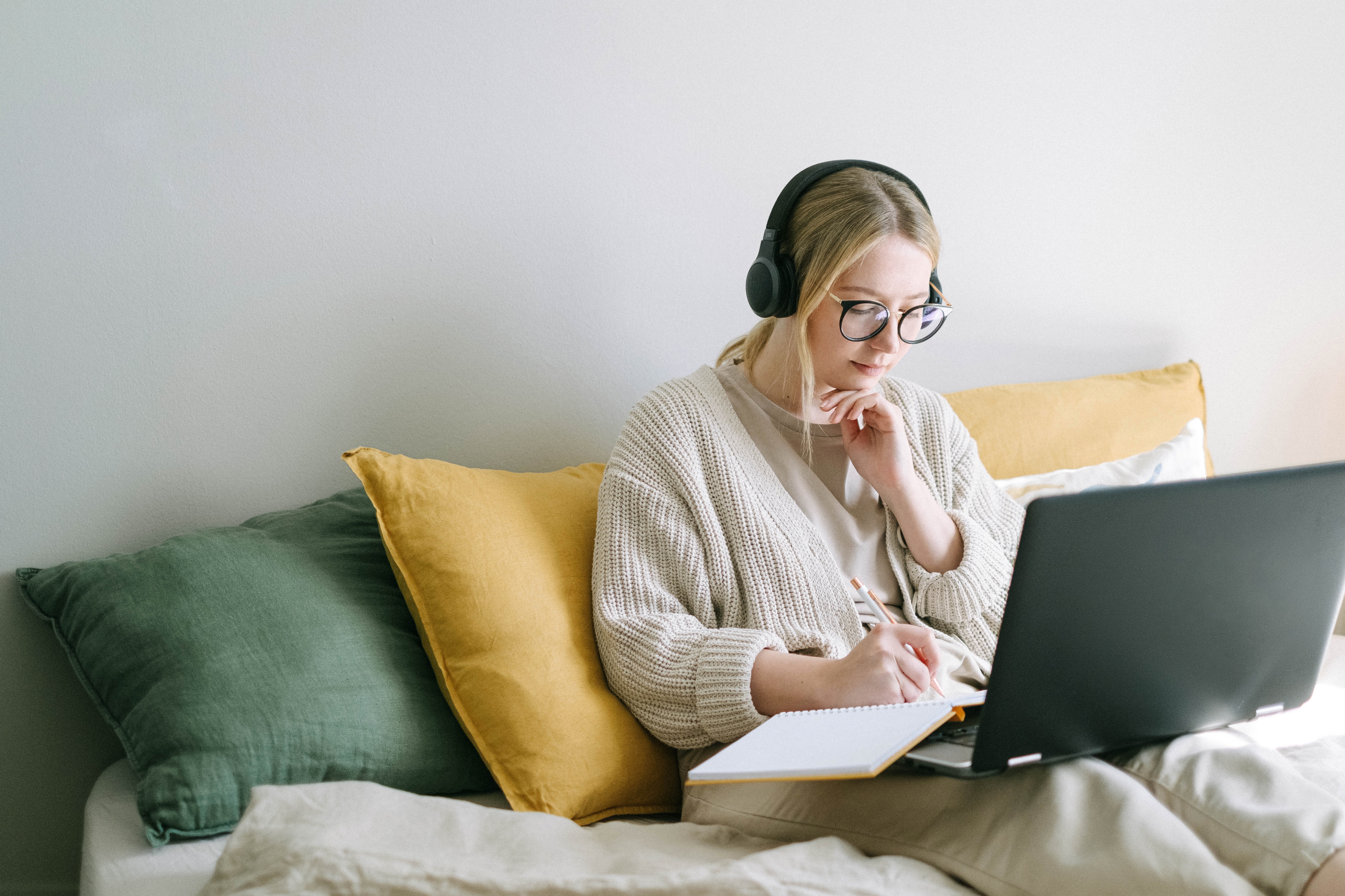 Paying Yourself First Budgeting Strategy Young woman comfy on couch with laptop and headphones