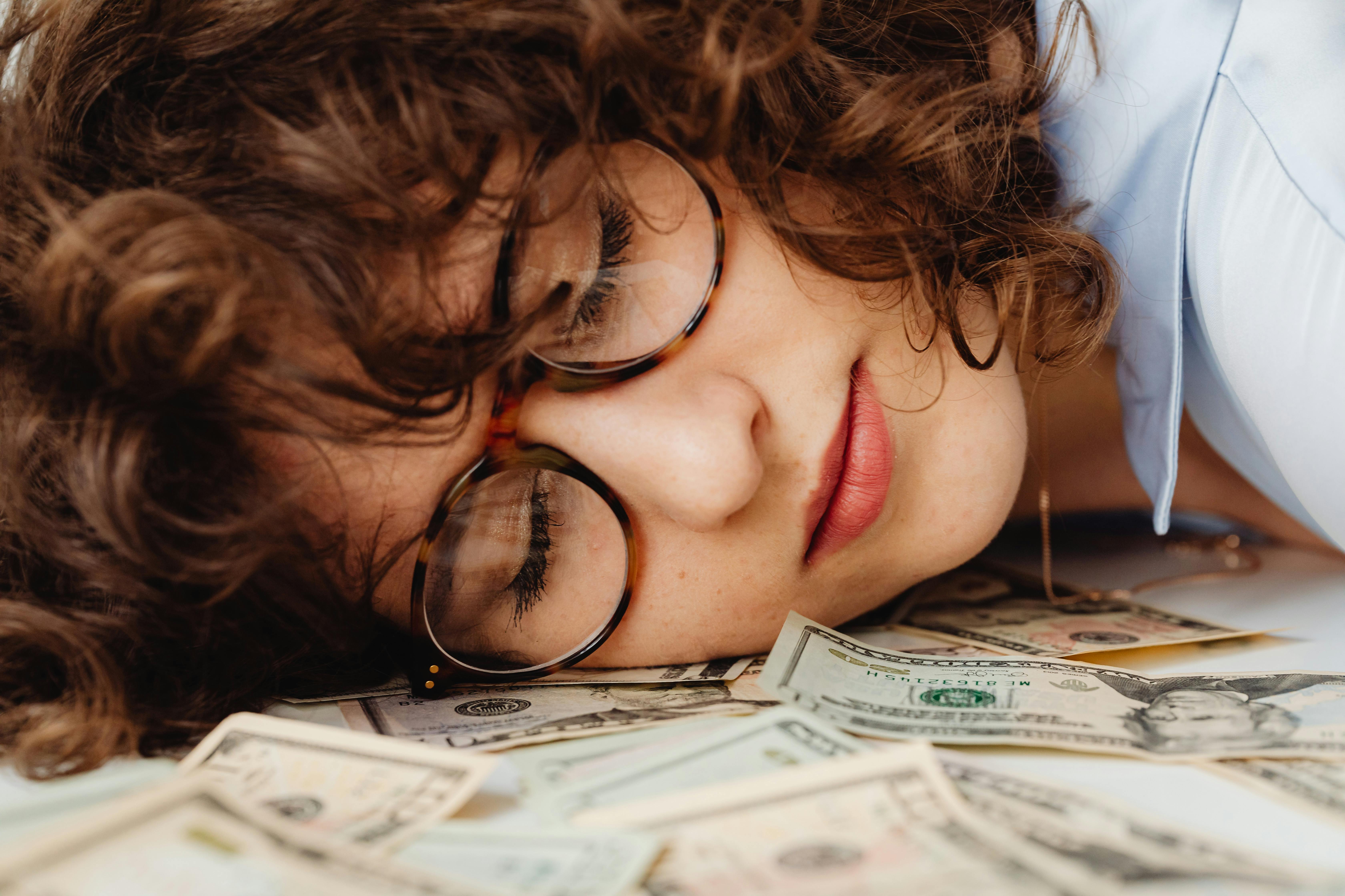 Woman sleeping with her head on a pile of money - do you dream of making a lot of money?